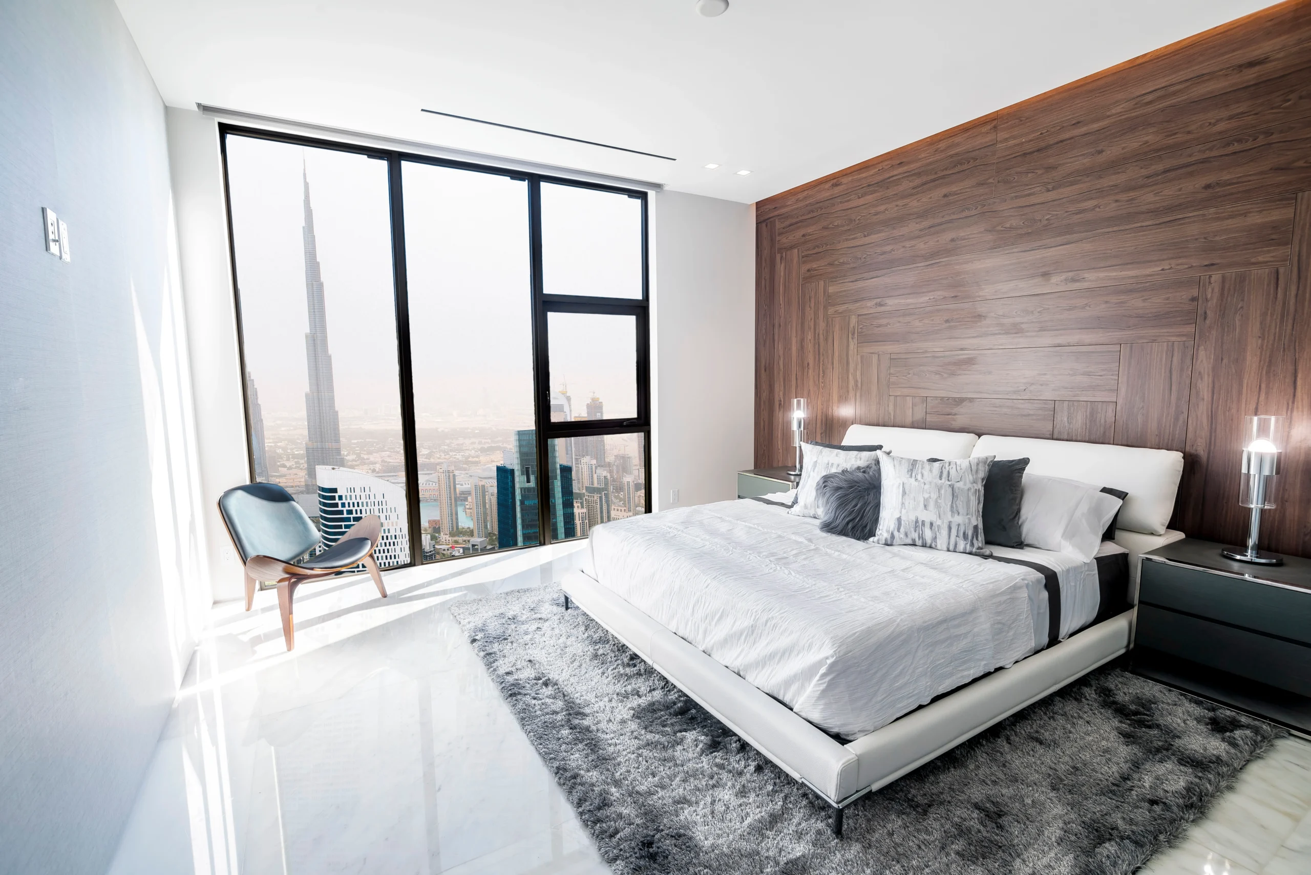 Modern and luxurious bedroom with white ceiling and wood accents with views of downtown Dubai skyline. Condo or Hotel accomodation.